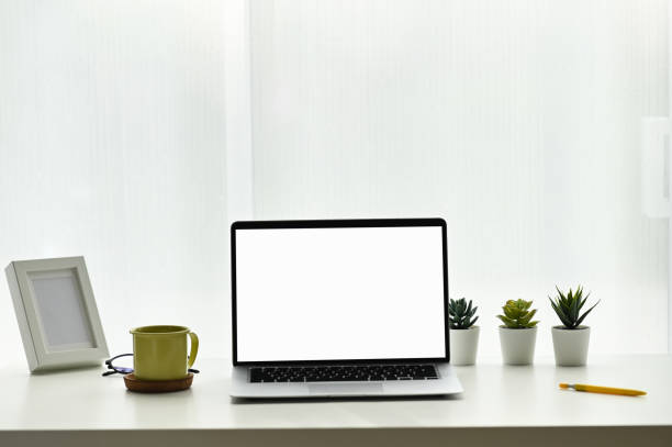 istock Front view of minimal workplace with empty screen laptop, plant, coffee cup and fram. For product montage. 1285020717