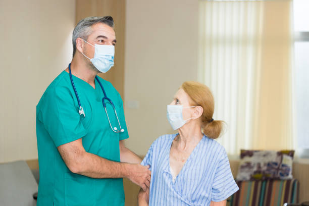 istock A nurse is guarding an elderly patient while both are wearing a surgical mask. 1285026506