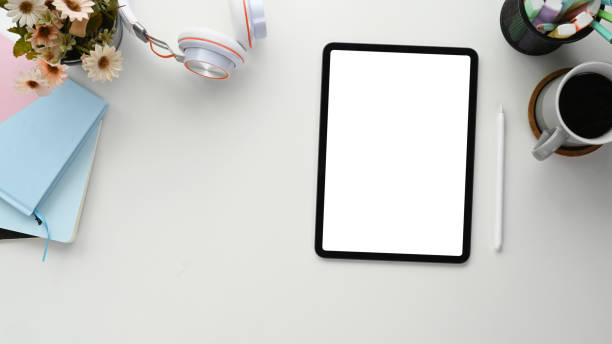 istock Flat lay photo of freelancer workspace with empty screen tablet, notebook, coffee cup and headphone on white table. 1285036195