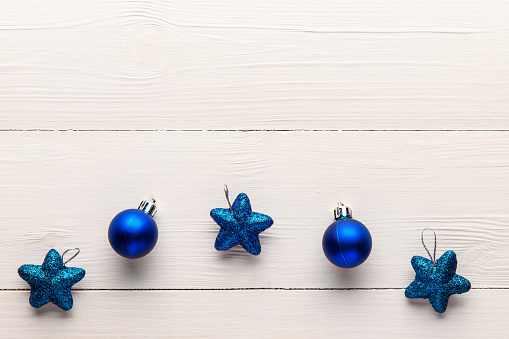 Blue Christmas toys on a light wooden background, with an empty space for text on top. New year and Christmas background