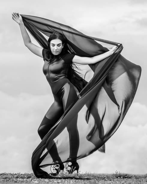 istock Woman in black overalls dancing with flying fabric 1285039188