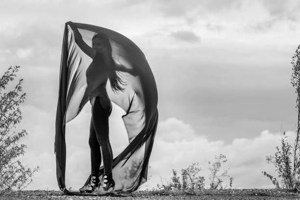 istock Woman in black overalls dancing with flying fabric 1285039233