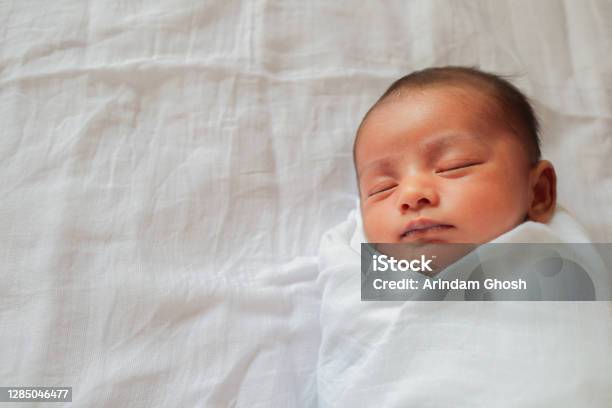 A One Month Old Baby Sleeping And Swaddled In White Cloth Lying In White Cloth Background Stock Photo - Download Image Now