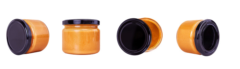 Delicious peanut almond paste in glass jar with black cap. Mock up isolated on white background. Peanut butter at different angles.