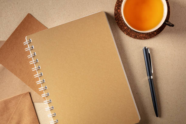 Journalling concept. Brown paper journal, top shot on a desk with a cup of tea and a pen Journalling concept. Brown paper journal, top shot on a desk with a cup of tea and a pen, the concept of free writing bullet journal photos stock pictures, royalty-free photos & images