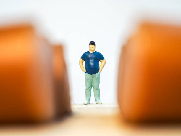 istock Miniature people : Close up fat man standing with sausages isolated on white background 1285050316