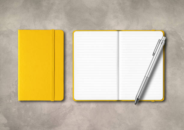 istock Yellow closed and open lined notebooks with a pen on concrete background 1285053170