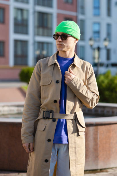 istock Young guy wears a modern coat, green hat, white jeans, and a sweater 1285055100