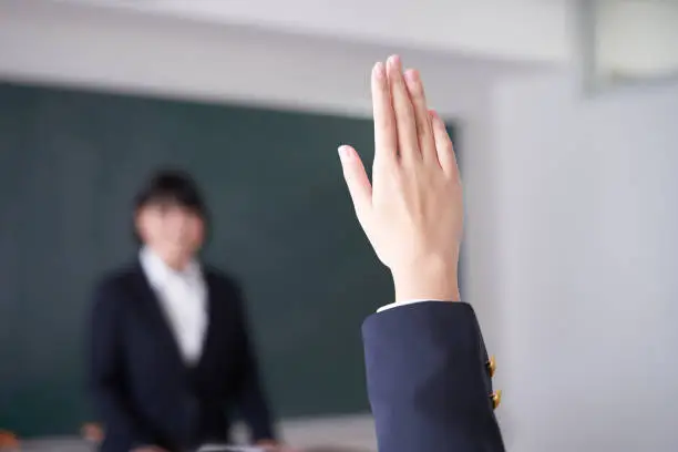 A Japanese junior high school girl raises her hand in the classroom