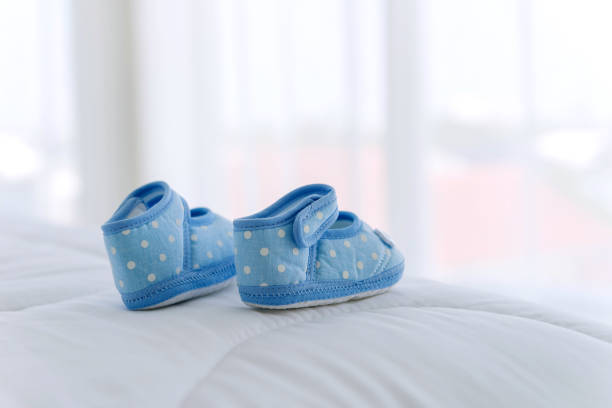 shoes For children On the holiday,Clothes, shoes For children placed in a white room with a hat, a clock, a toy for the background. baby booties stock pictures, royalty-free photos & images