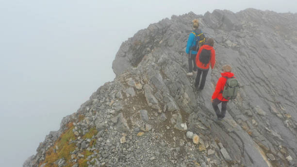 istock Three people climb a mountain on a foggy day 1285059931