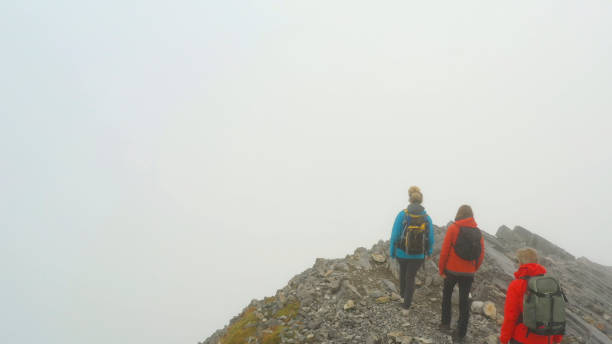 istock Three people climb a mountain on a foggy day 1285060582