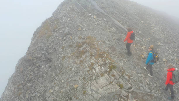 istock Three people climb a mountain on a foggy day 1285060653