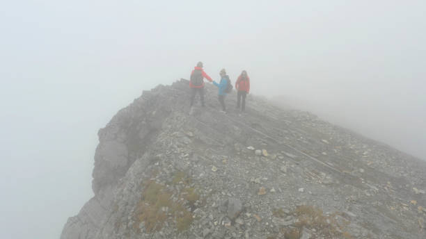 istock Three people climb a mountain on a foggy day 1285060654