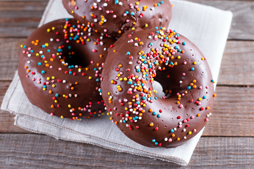 Donut with Chocolate Icing and Sprinkles on a wooden table