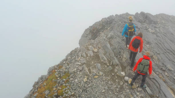 istock Three people climb a mountain on a foggy day 1285060799