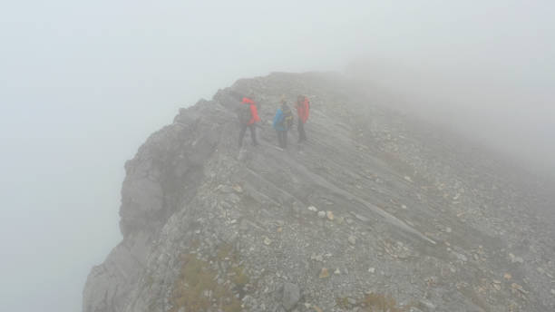 istock Three people climb a mountain on a foggy day 1285060818