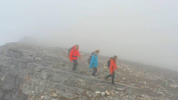 istock Three people climb a mountain on a foggy day 1285060866