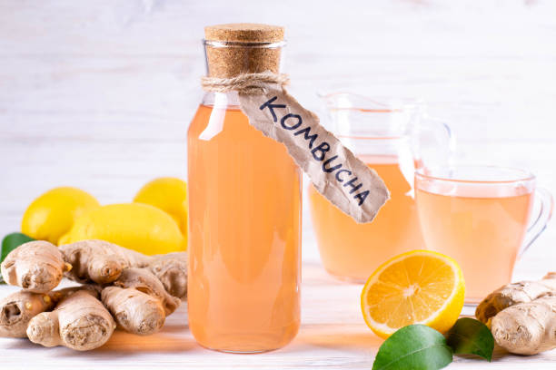 Refreshing filtered kombucha tea in a glass bottle and a glass, with label written kombucha on white wooden table. Refreshing filtered kombucha tea in a glass bottle and a glass, with label written kombucha on white wooden background. compote photos stock pictures, royalty-free photos & images
