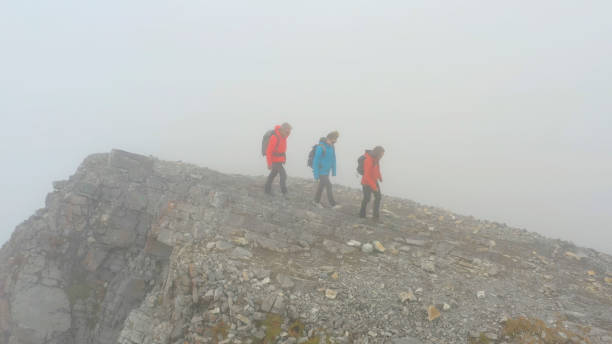 istock Three people climb a mountain on a foggy day 1285061004