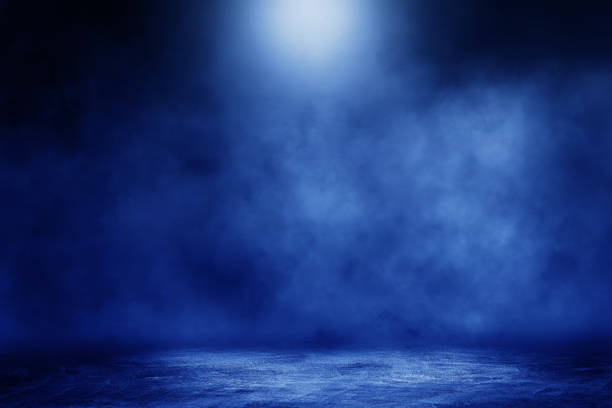 istock Studio dark room concrete floor grunge texture background with blue lighting effect and smoke in background. 1285064902