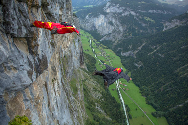 los pilotos del traje de ala saltan de la cresta de la montaña por la mañana - salto desde acantilado fotografías e imágenes de stock