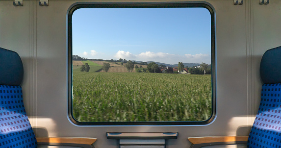 An empty blue seat in europe german train with window corn field display nature summer view