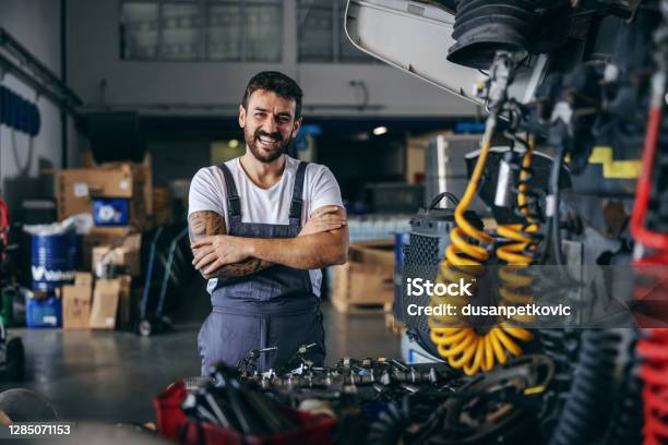 Smiling Happy Bearded Tattooed Worker In Overalls Standing Next To Truck With Arms Crossed Stock Photo - Download Image Now