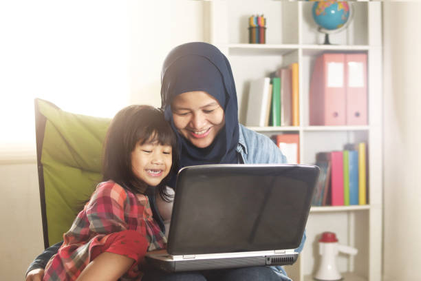 asian muslim mom and little baby girl daughter learning online or watching videos on laptop, happiness between mother and kid, single parent being happy - child computer laptop little girls imagens e fotografias de stock