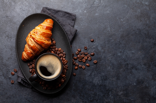 Espresso coffee and croissant for breakfast. Top view flat lay with copy space