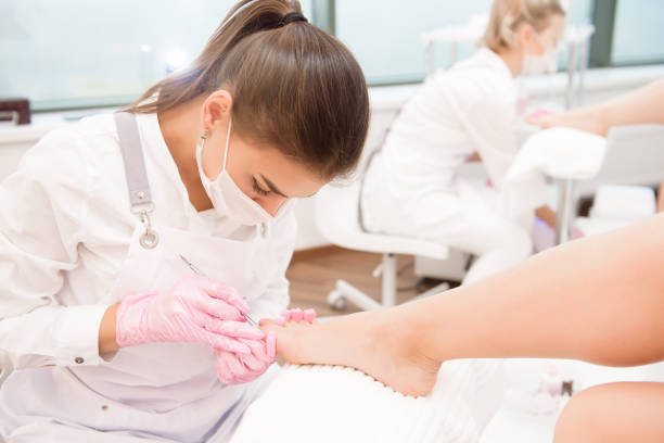 foot treatment for two friends or sisters in spa salon. nail artist in beauty salon making pedicure for clients feet. - podiatrist customer service beauty spa imagens e fotografias de stock