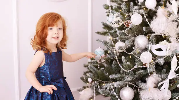 Little girl. Happy child. Blue dress. Christmas decorations.