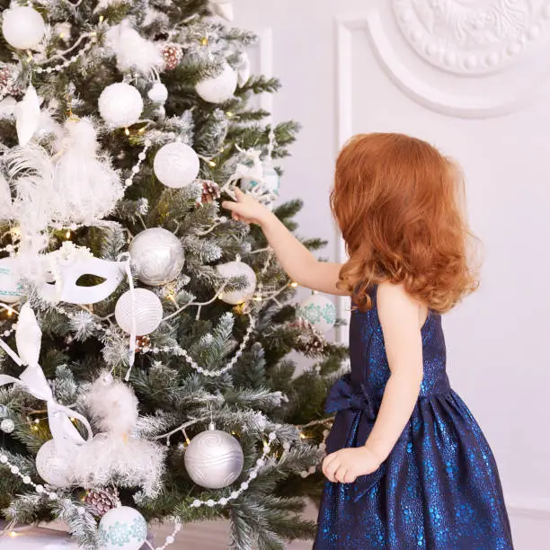 Little girl. White background. Blue dress. Christmas decorations.