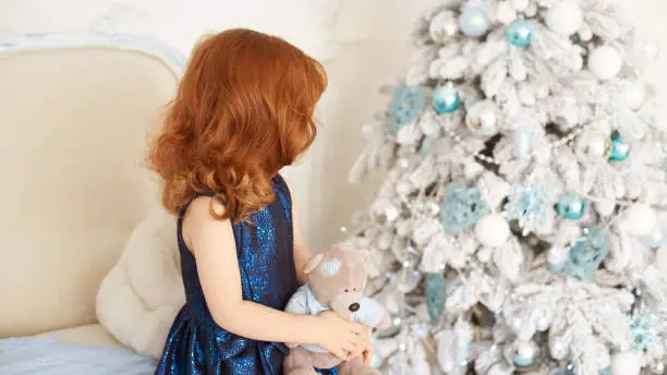 Little girl. Christmas interior. Blue dress. Horizontally.