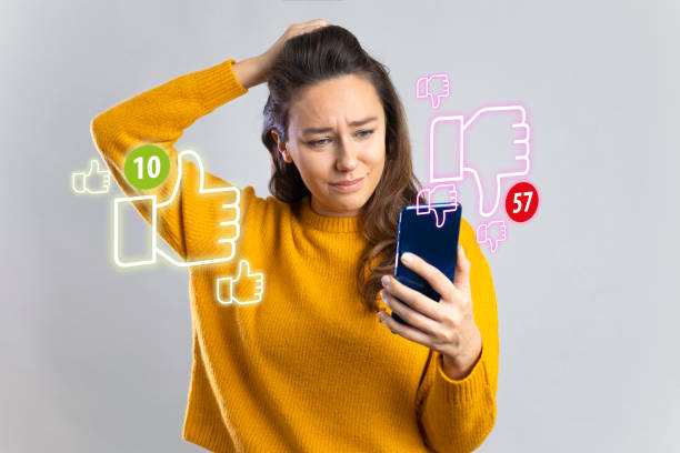 Young woman holding mobile phone looking too much dislikes on her social media post stock photo