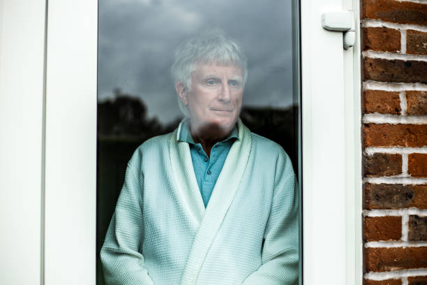istock Depressed senior man looking out of window 1285080207