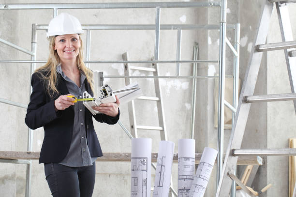 istock smiling woman architect or construction interior designer with with meter measuring white windows cutaway profile inside a building site with ladder and scaffolding in the background 1285081723