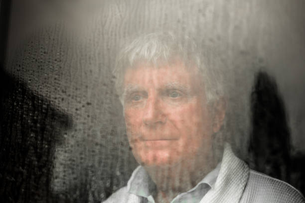 istock Depressed senior man looking out of rainy window 1285083378