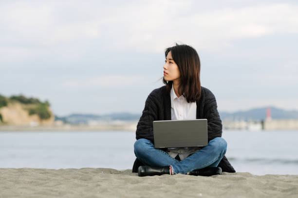 Young woman working from beach Work and vacation: young woman telecommuting from beach fujisawa kanagawa photos stock pictures, royalty-free photos & images