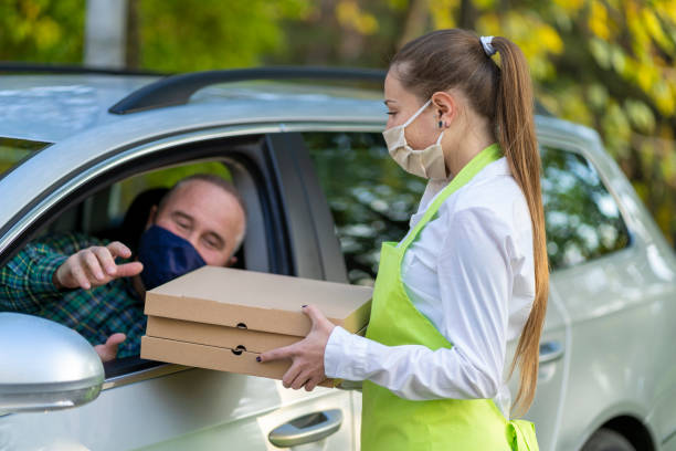 istock Order Being Passed Between  Hands Through Car Window Outside Restaurant During Covid-19 Lockdown 1285085366