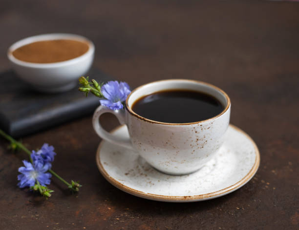 café de achicoria y flores azules sobre un fondo marrón oscuro. raíz de achicoria molida en un tazón. - inulin fotografías e imágenes de stock