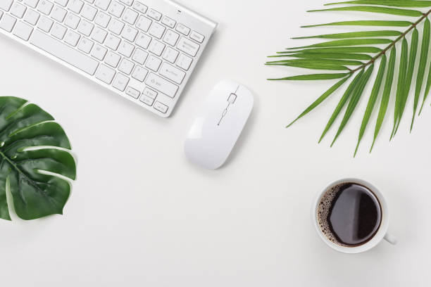 istock Workspace with computer keyboard, office supplies, green leaf, and coffee cup on white background. 1285093597