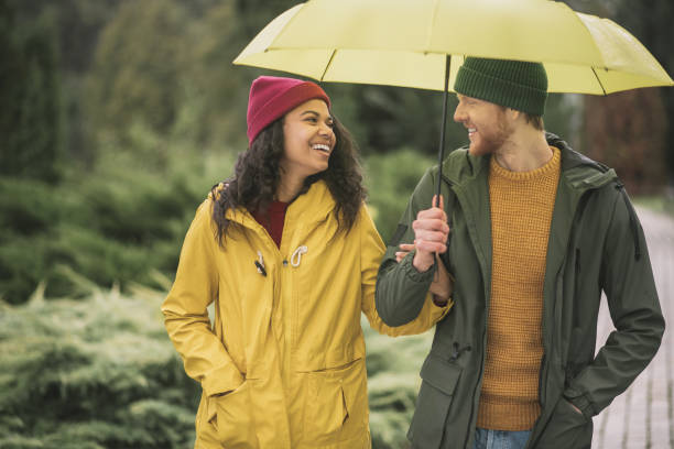istock Young couple under yellow umbrela looking happy 1285094665