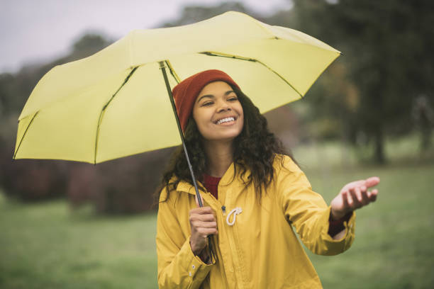 istock Cute mulatta with yellow umbrella looking joyful 1285094670