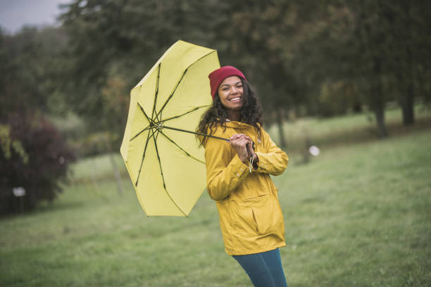 istock Cute mulatta with yellow umbrella looking cheerful 1285094679