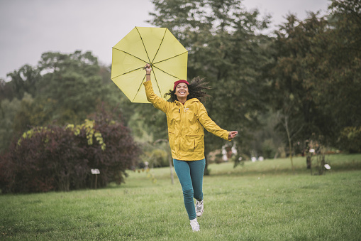 Fun. Cute mulatta with yellow umbrella running and having fun