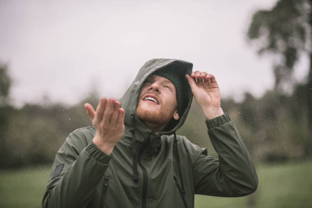 istock Young man in a green coat catching rain drops 1285094759
