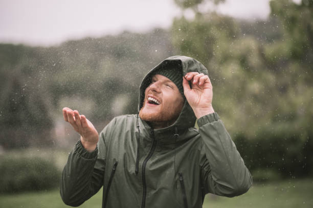 istock Young man in a green coat catching rain drops 1285094765