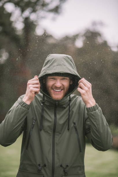 istock Young man in a green coat walking in the rain and smiling 1285094766