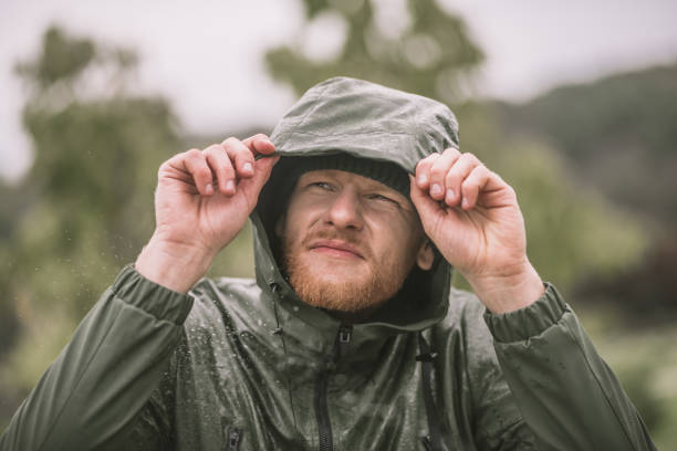 istock Young bearded man in a hood standing under the rain 1285094770